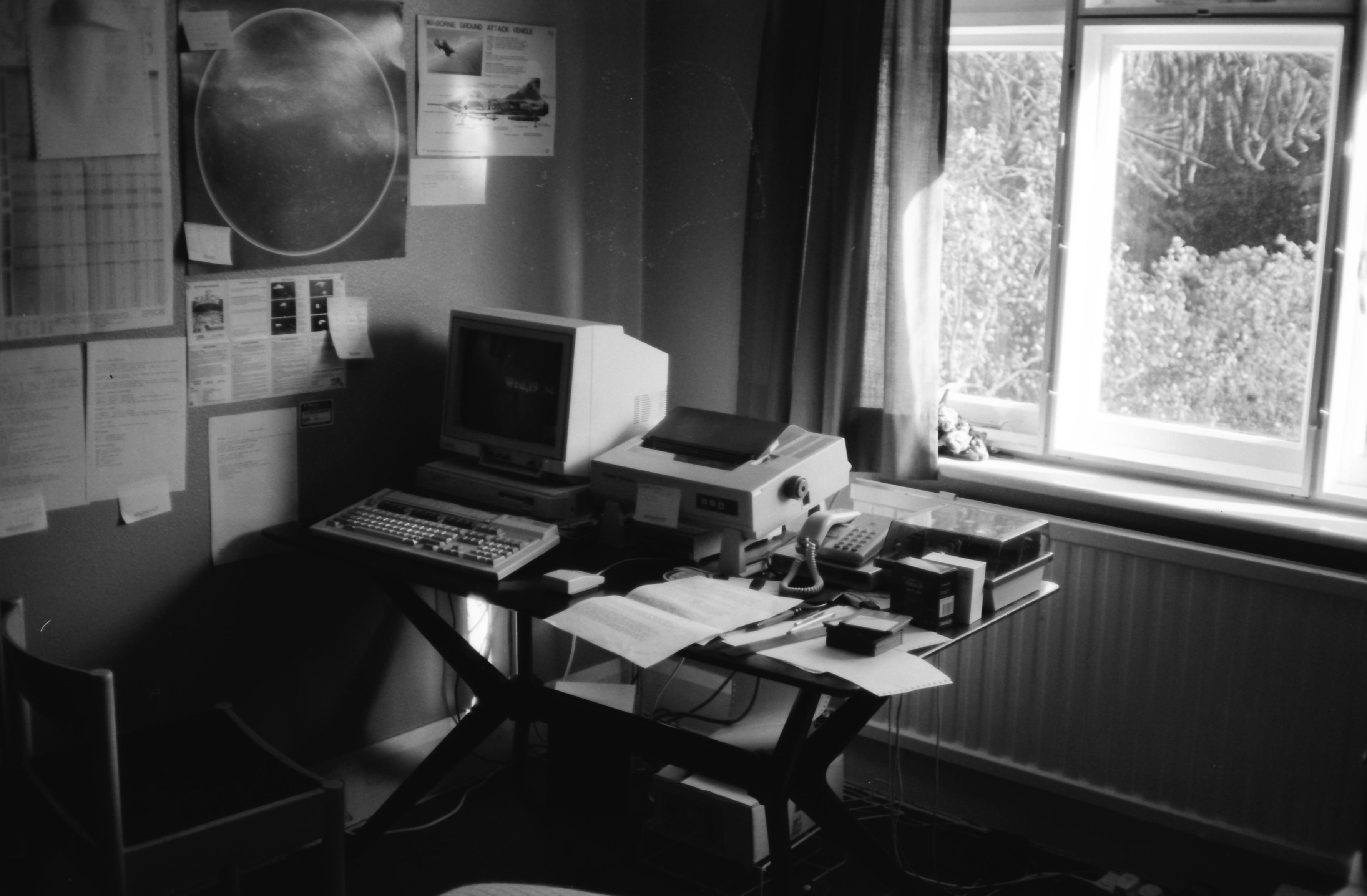 Acorn A310 with monitor and keyboard, dot-matrix printer and telephone on a table in front of a window.